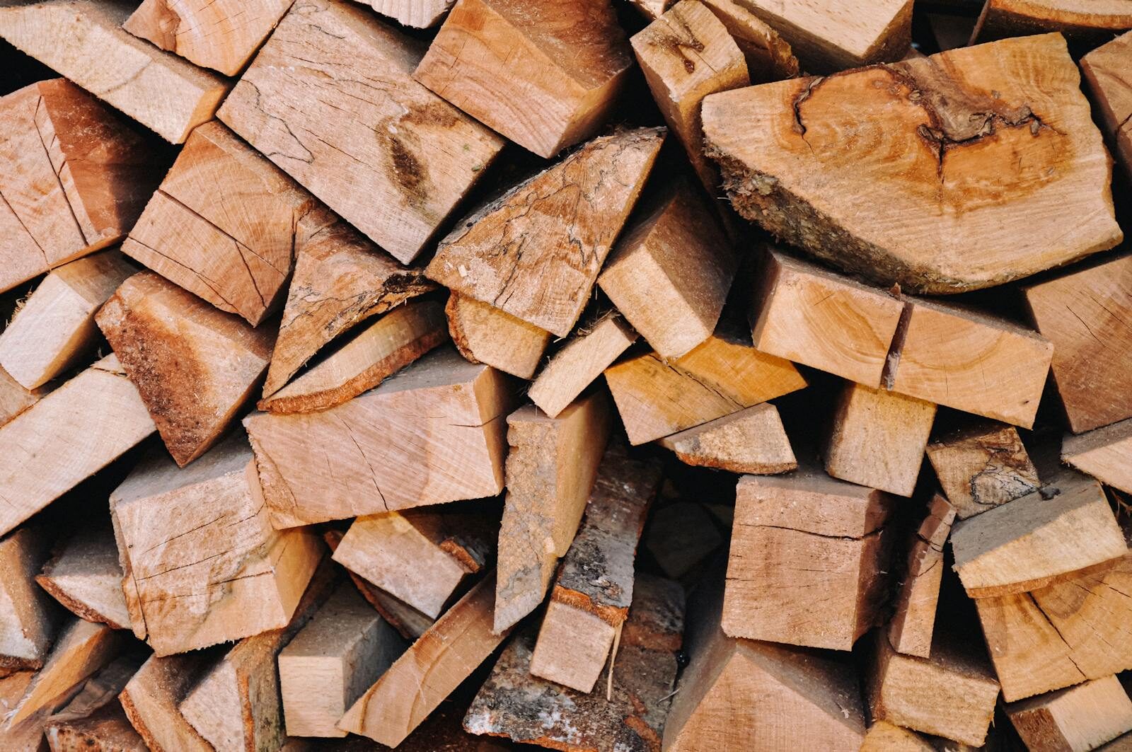 Stacked split firewood logs representing wood biomass fuel where representative sampling of moisture content and quality is essential for accurate energy yield assessment.