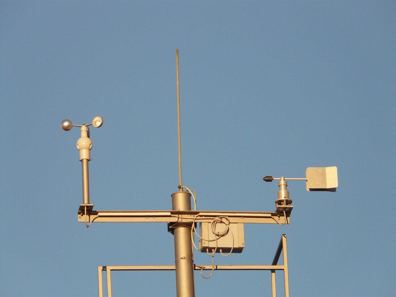 Cup anemometer and wind vane mounted on a weather station mast measuring continuous wind speed and direction for environmental field research monitoring.