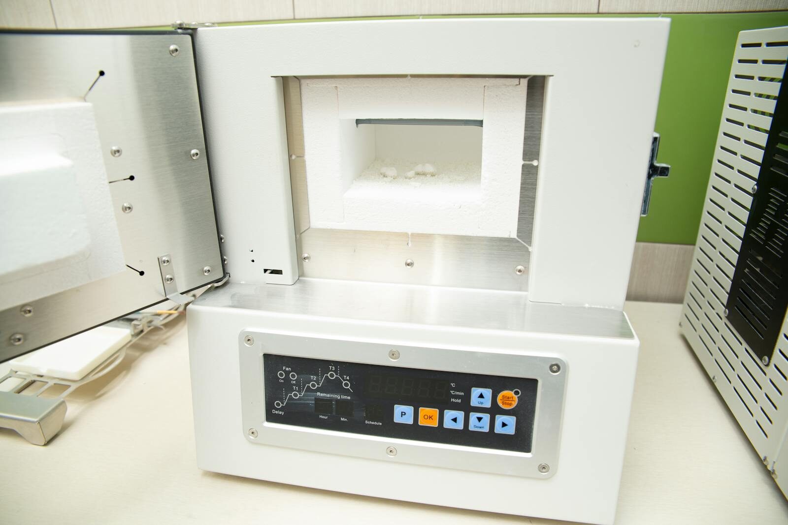 Small laboratory drying oven with digital temperature controller open on a lab bench used for drying soil and plant samples for water content and dry weight analysis in ecological research.
