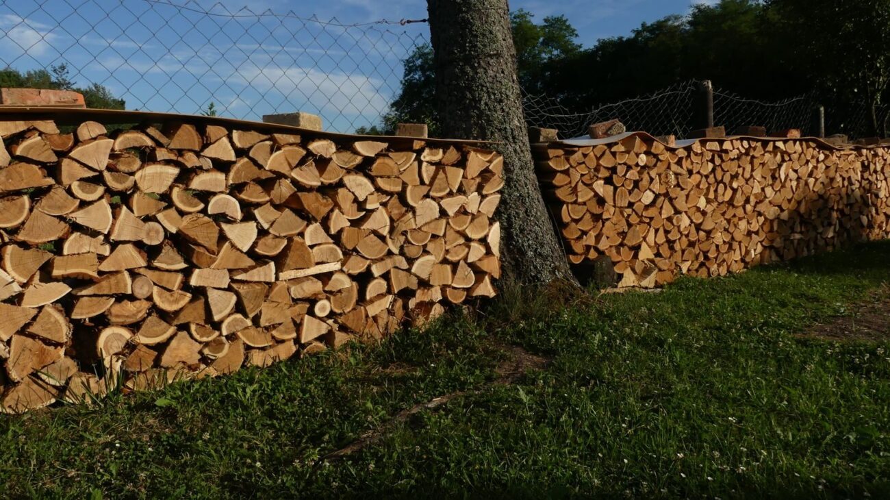 Long neat stack of split firewood drying outdoors on grass with the split faces exposed
