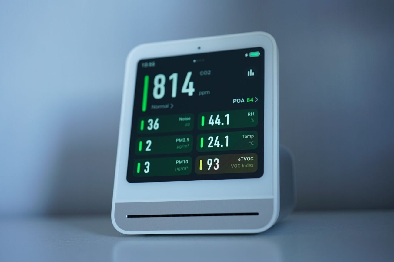A digital air quality monitor displaying particle and air readings on its screen