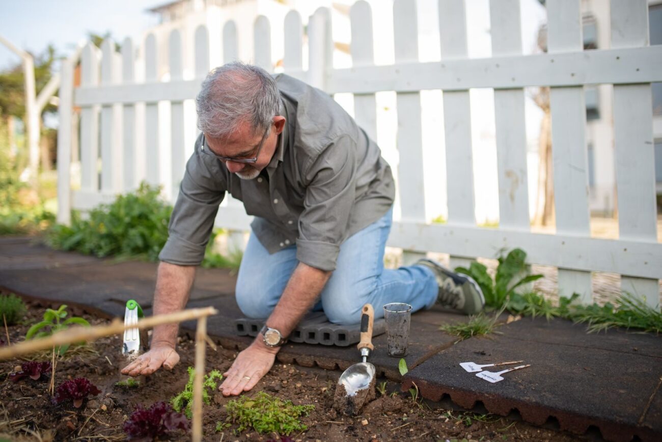 Person kneeling beside a raised bed taking soil samples for testing