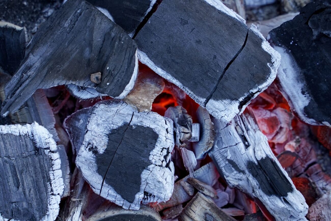 Dark charcoal and glowing embers showing the carbon rich solid residue produced when wood undergoes thermal decomposition similar to the biochar product of biomass pyrolysis