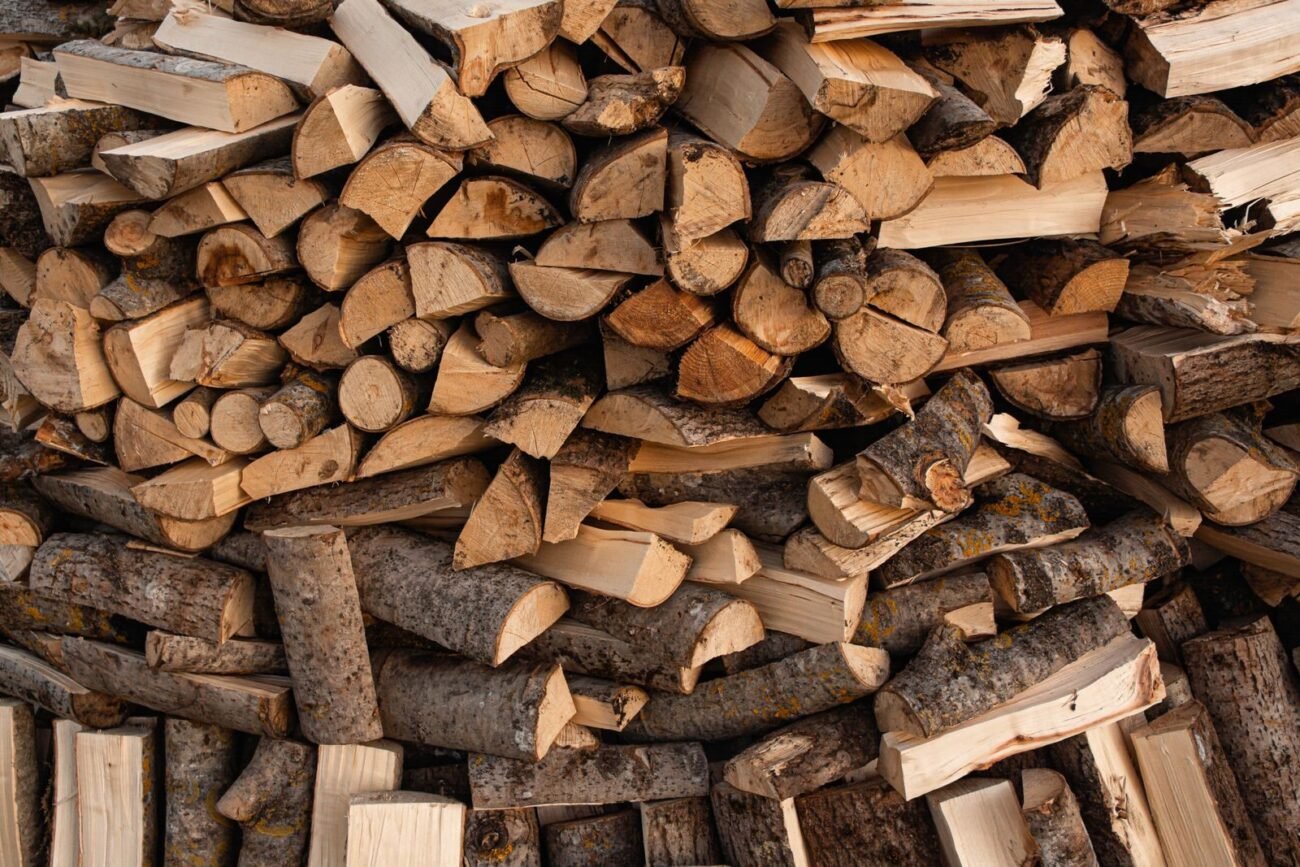 Firewood carrier filled with split, seasoned logs, with an axe and work gloves
